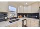 Kitchen features stainless sink, quartz countertops, subway tile backsplash, and white cabinets at 4874 S Lincoln St, Englewood, CO 80113