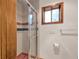 Shower featuring glass doors, tiled walls, and a window with wood trim at 103 Red Wing Ct, Mead, CO 80542