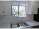 Kitchen sink and window provides a view of the tree-filled outdoors and features white cabinets and subway backsplash at 2215 S Buckley Rd # 201, Aurora, CO 80013