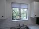 Kitchen sink and window provides a view of the tree-filled outdoors and features white cabinets and subway backsplash at 2215 S Buckley Rd # 201, Aurora, CO 80013