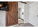 Hallway with dark brown sliding door leading to an ensuite bathroom with white cabinetry and a granite countertop at 4548 River Highlands Loop, Elizabeth, CO 80107