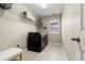 Modern laundry room with tiled floors, front-loading washer and dryer, and overhead shelving at 21028 E Saratoga Ave, Aurora, CO 80015