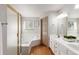 Bathroom featuring wood floors, a double vanity, and a corner tub with glass enclosure at 1832 S Tamarac St, Denver, CO 80231