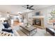 Bright living room with a brick fireplace, ceiling fan, and seamless flow to the modern white kitchen at 1832 S Tamarac St, Denver, CO 80231