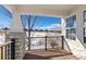 Covered outdoor living space with wood floors and black metal railing overlooking a greenbelt at 7879 S Zante Ct, Aurora, CO 80016
