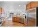Open kitchen with wood floors, stainless steel refrigerator, and views of the dining and living areas at 7879 S Zante Ct, Aurora, CO 80016