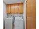 Functional laundry room with white washer and dryer units, complemented by natural wood cabinets for ample storage at 7879 S Zante Ct, Aurora, CO 80016