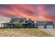 Gray two-story house with a large front porch, three-car garage, and beautiful sunset at 402 S County Road 129, Bennett, CO 80102