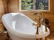 Close-up of a luxurious standalone tub and gold fixtures in a rustic bathroom at 451 Harris Dr, Idaho Springs, CO 80452