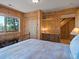 Cozy bedroom with wood paneled walls, a metal bed frame and a window overlooking mature trees at 451 Harris Dr, Idaho Springs, CO 80452