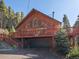 Attractive cabin featuring large windows, a spacious deck, and garage, surrounded by a lush green forest at 451 Harris Dr, Idaho Springs, CO 80452