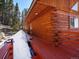 Exterior of a wooden cabin with snow covered grounds and a red deck at 451 Harris Dr, Idaho Springs, CO 80452