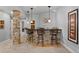 Basement bar area featuring stone accents, pendant lighting, and seating for entertaining guests at 7050 S Polo Ridge Dr, Littleton, CO 80128