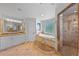 Bright bathroom features a soaking tub with stone surround, marble vanity, and glass-enclosed shower at 7050 S Polo Ridge Dr, Littleton, CO 80128