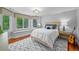 Inviting bedroom featuring large windows, bench seat, hardwood floors, and a patterned accent rug at 7050 S Polo Ridge Dr, Littleton, CO 80128