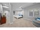 A well-lit bedroom with beige carpet and a queen bed with decorative blue throw pillows and a gray armchair at 7050 S Polo Ridge Dr, Littleton, CO 80128