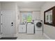 Well-lit laundry room includes modern washer and dryer, utility sink, window, and ample cabinet space at 7050 S Polo Ridge Dr, Littleton, CO 80128