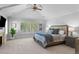 Serene main bedroom boasts a vaulted ceiling, plush carpet, ceiling fan, and large windows with tree views at 7050 S Polo Ridge Dr, Littleton, CO 80128