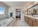 Bright bathroom featuring a soaking tub with tile surround, double sinks and view to the primary bedroom at 145 Kettle Valley Way, Monument, CO 80132