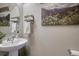 Elegant powder room with pedestal sink, decorative mirror, and artwork at 145 Kettle Valley Way, Monument, CO 80132