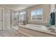 Bright bathroom featuring a soaking tub, tiled walk-in shower and a large window with blinds at 145 Kettle Valley Way, Monument, CO 80132