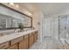 Bathroom featuring double sinks with wood cabinets, quartz countertops, large mirror and walk-in shower at 145 Kettle Valley Way, Monument, CO 80132