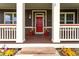 Inviting front porch with vibrant flowerpots flanking the red door and decorative columns at 5137 Mt Arapaho Cir, Frederick, CO 80504