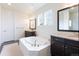 Bathroom with soaking tub, dark wood cabinets, granite countertops, and large mirrors at 11880 W 38Th Pl, Wheat Ridge, CO 80033