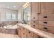 Bright bathroom featuring a soaking tub, wood cabinets, and a large vanity mirror at 9470 S Silent Hills Dr, Lone Tree, CO 80124