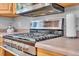 Close-up of a stainless steel gas range cooktop with modern vent hood in a well-appointed kitchen at 16941 E Eastman Pl, Aurora, CO 80013