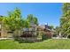 Wide shot of a large backyard with patio, deck, lush trees, and green grass at 11035 W 26Th Pl, Lakewood, CO 80215