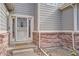Close-up of the front entrance with a secure screen door and brick accents at 9306 W 13Th Pl, Lakewood, CO 80215