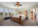 Well-lit Primary bedroom with a view of the backyard, a ceiling fan and adjacent en-suite bathroom at 6047 Vacquero Cir, Castle Pines, CO 80108