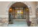 Close-up of a charming front entryway with stone archway and decorative metal gate, creating a welcoming feel at 6047 Vacquero Cir, Castle Pines, CO 80108