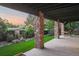 A covered stone patio features a grass lawn, plants, and an orange swing chair in the backyard at 6047 Vacquero Cir, Castle Pines, CO 80108