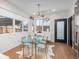 Bright dining area with modern chandelier and glass table, adjacent to an entryway and a door at 1260 Newton St # 1, Denver, CO 80204