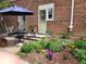 Brick patio includes a wrought-iron table set amidst a flower garden and brick pavers at 1165 Krameria St, Denver, CO 80220