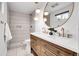 Modern bathroom with double vanity, gold fixtures, walk-in shower, and unique round mirror at 9565 W 12Th Pl, Lakewood, CO 80215