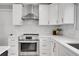 Renovated kitchen with stainless steel appliances, range hood, and white shaker cabinets at 9565 W 12Th Pl, Lakewood, CO 80215