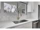 Kitchen featuring marble backsplash, stainless steel sink and appliances, quartz countertop and modern gold faucet at 9565 W 12Th Pl, Lakewood, CO 80215