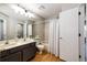 Bathroom featuring dual sinks, wood floor, tub shower, and door to bedroom at 8231 S Fillmore Way, Centennial, CO 80122