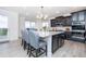 Modern kitchen with black cabinets, a large island with bar stools, and stainless steel appliances at 16701 Buffalo Run Dr, Commerce City, CO 80022