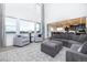 An airy living room with large windows, gray seating, and an open floor plan to dining area at 16701 Buffalo Run Dr, Commerce City, CO 80022