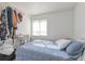Bright bedroom features a cozy blue quilt, white walls, and natural light from a large window at 12134 Glencoe St, Thornton, CO 80241