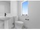 A bathroom featuring a pedestal sink, low-flow toilet, and a window providing natural light at 14245 Currant St, Broomfield, CO 80020