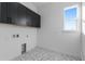 A bright laundry room featuring modern gray cabinets and stylish geometric-patterned flooring at 14245 Currant St, Broomfield, CO 80020