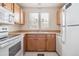 Well-lit kitchen featuring wooden cabinets, a white refrigerator, and a window above the sink at 4656 S Dillon Ct # D, Aurora, CO 80015