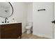 Modern powder room featuring black hardware, wood vanity, white counter, toilet at 7114 S Costilla St, Littleton, CO 80120