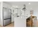 Modern kitchen with white cabinetry, stainless steel refrigerator, and a spacious kitchen island with barstool seating at 7114 S Costilla St, Littleton, CO 80120