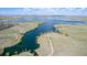 Expansive aerial view of a lake, surrounding open land, and a distant neighborhood, highlighting the community's natural setting at 7202 S Valleyhead Ct, Aurora, CO 80016